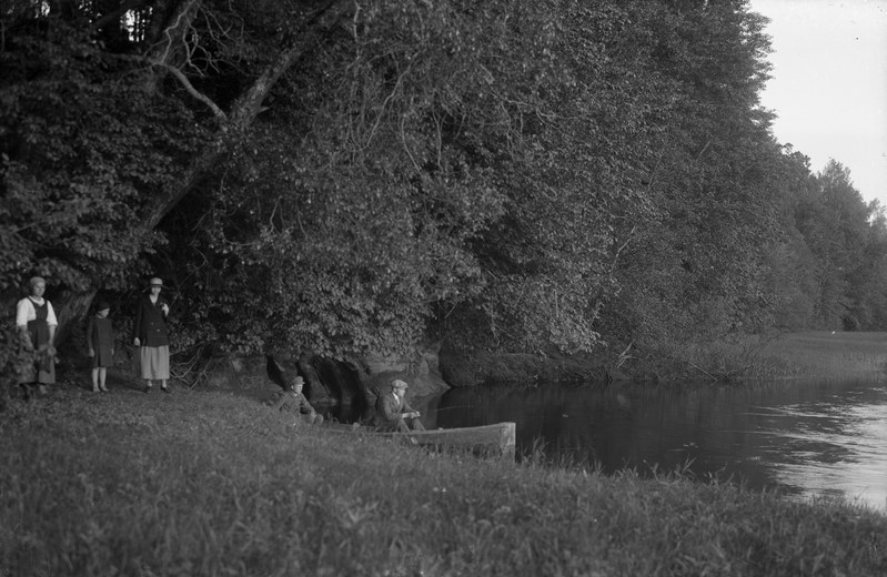 Inimesed veekogu ääres, kaks meest paadis.