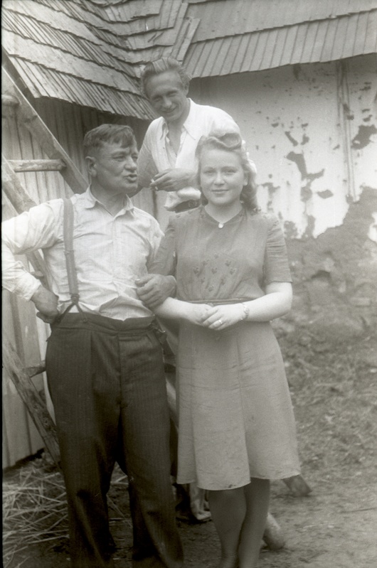 Mees ja naine seismas kuuri taustal, mees nende selja taga redelil (Rõngu kiriku leer)