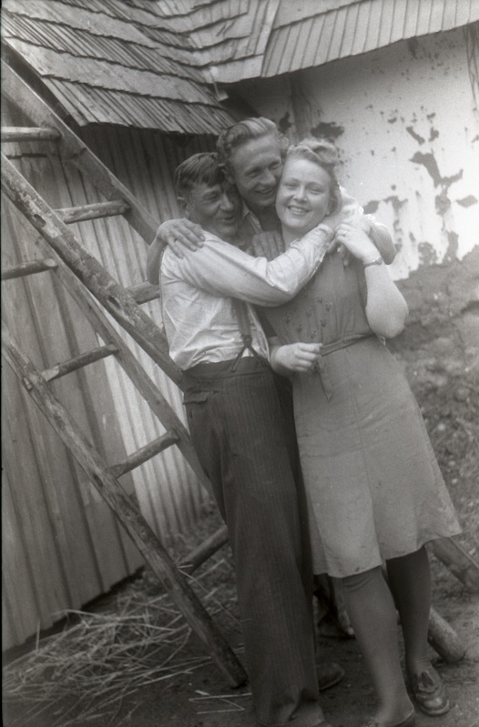 Mees ja naine seismas kuuri taustal, mees nende selja taga redelil (Rõngu kiriku leer)