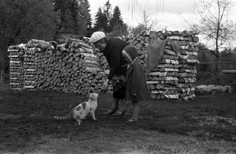 Naine lapse ja kassiga puuriida taustal (Pulk ja Lukk lapsega)
