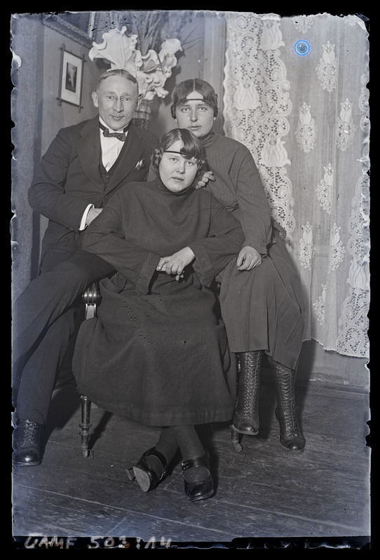 Hermann Jaakson koos kahe noore naisega. Toolile toetumas