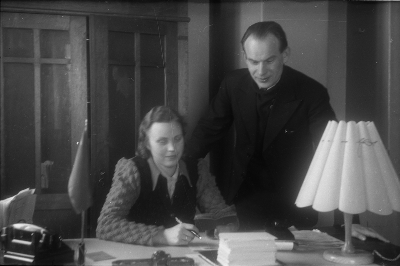 Naine ja mees kirjutuslaua taga istumas ja seismas (TRÜ töötajad, ülikooli ametnikud)