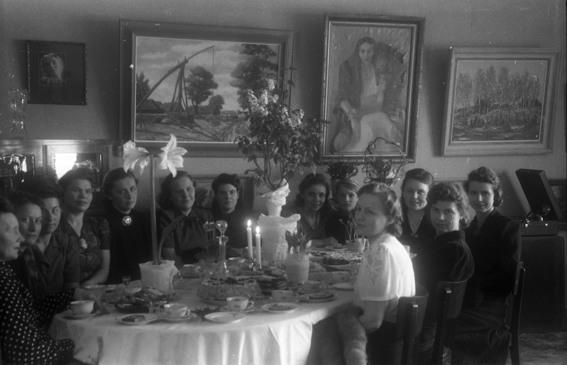 Tartu polikliiniku laboriarst Maria Jansen-Ora (vasakult kaheksas) koos tütre Liiviaga? (vasakult üheksas) ning seltskonnaga ümber laua istumas (dr Ora oma perega)