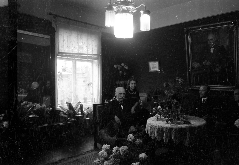 Johannes Voldemar Veski (vasakul), tema tütar Asta Veski, Paul Ariste (paremalt teine) ja mees elutoas istumas (Johannes Voldemar Veski 70. sünnipäeva tähistamine)