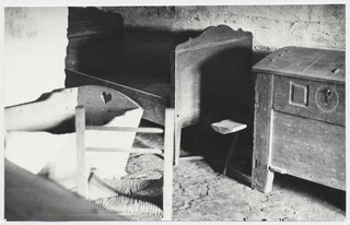 Eeru kõrtsi tagakamber: näha puuvoodi, riidekirst, häll, puupink ja õlgpõhjaga tool