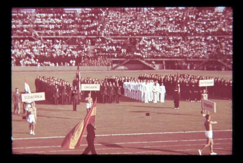 Üliõpilasspordipidu Viinis 1939, avamisüritus. Vaade staadionile, Hispaania lipp ees, taga grupid lippude ja riiginimesiltidega - Südafrika, Ungarn, Deutschland.