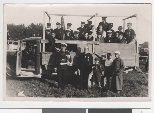 Group photo, fire-fighting form and private idea for people in the truck box and on its front. 1930s.