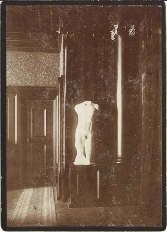 Alatskivi. Interior of the manor. On the left side, the dark door, the ancient male sculpture (only the body and part of the feet) in the middle of the dark post office, alongside the dark pillar with the capita line
