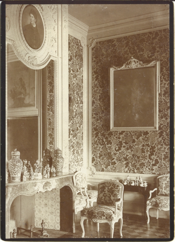 Alatskivi. Interior of the manor. On the left of the fireplace, on the front of the fireplace, beauty bags, mirror on the wall, one portrait. Next to the fireplace and in front of the fireplace, four support chairs, a light table with beauty. Wall portrait. Walls killed with flower clothes.