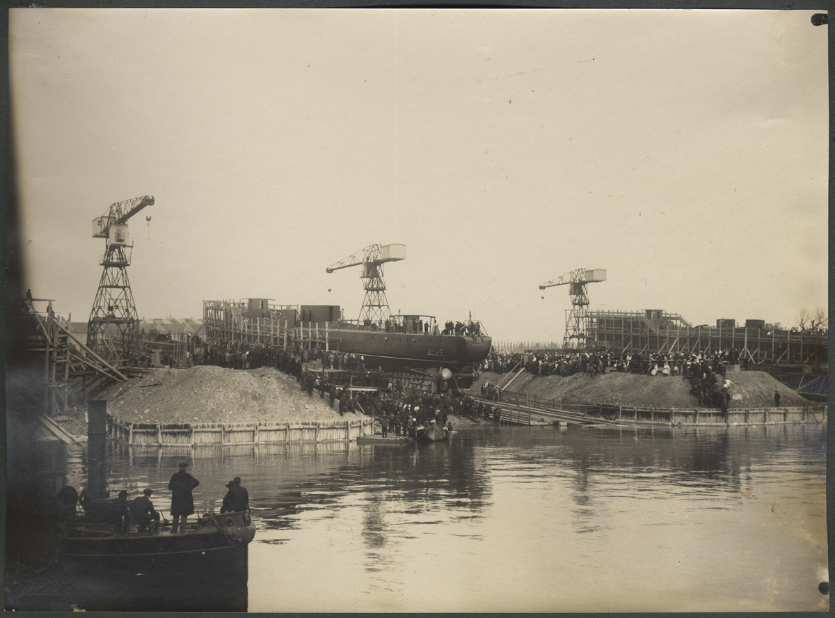 Russian-baltic shipyard. At the forefront, there were a number of people, at least one of which has a form of a Czar-Russia sea officer on the back. In the back of the edge, a slider appears to be a flood of a waterproof ship. Making a ship's solemn watering