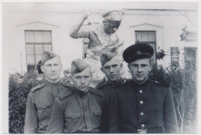 Photocopy Group of young men Kärdla kneeled in front of the diner in the background of sculpture