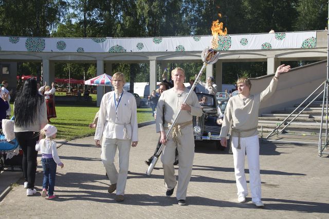 Digital photo. Tartu Laulupidu 2014. Singing party train walking to the song field. Lighters: Martin Four, Indrek Teino and Veiko Vunder. The old car with the characters of the ZIC song-upeo.