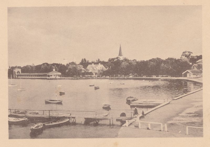 Foto. Suur Promenaad Haapsalus. Vasakul "Trinkhalle". Esiplaanil lahesopp paadisilla ning ankurdatud paatidega.