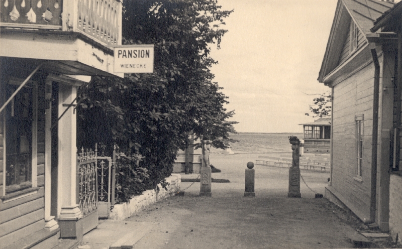 Fotopostkaart. Vaade Kõlakoja tänavalt Tagalahe suunas, esiplaanil pansion Wienecke sissepääs, tagaplaanil Lillekandjad tänava otsas.