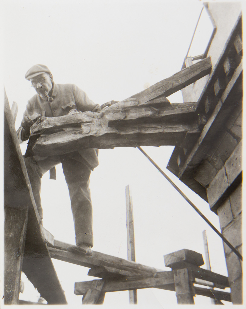Akseli Gallen-Kallela on the tower of Tarvaspää working on a dragon-shaped gargoyle, 1927; photograph 3.