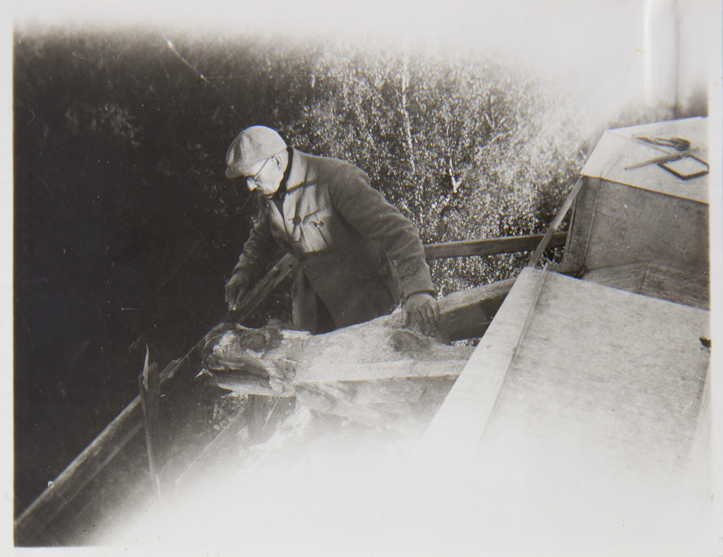 Akseli Gallen-Kallela on the tower of Tarvaspää working on a dragon-shaped gargoyle, 1927; photograph 4.