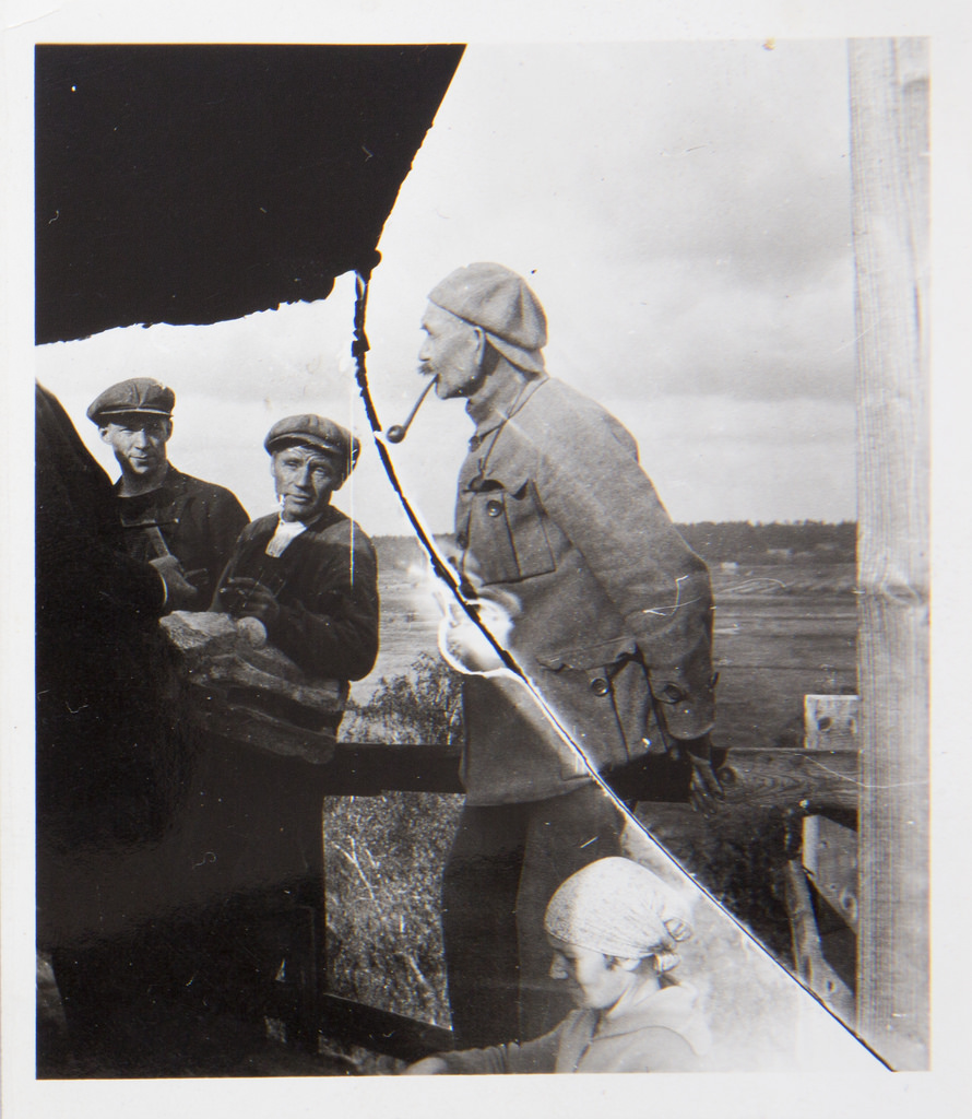 Akseli Gallen-Kallela with a pipe in his mouth, sculptor Alpo Sailo (the hand with a hammer on the left) and workers on the tower of Tarvaspää, 1927.