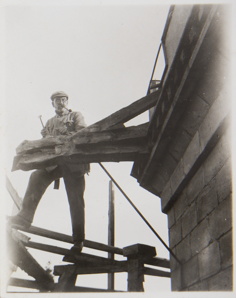 Akseli Gallen-Kallela at Tarvaspää´s tower working on a dragon-shaped gargoyle, 1927; photograph 1.