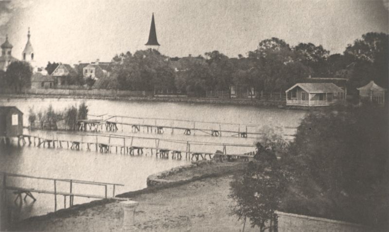 Foto. Vaade Suurele Promenaadile Supluse tänava algusest. Esiplaanil postament päiksekellaga kaldapealsel ja suplussillad. u. 1870.