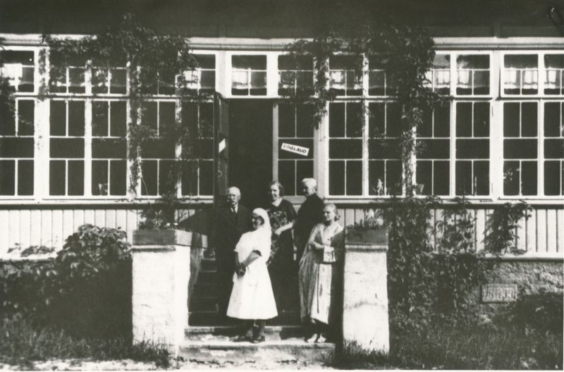 Foto. Töötajad linna mudaravila (end. Bergfeldt) trepil. Vasakult: mudaravila direktor Gustav Akleberg, kassapidaja Elfriede Antov (sünd.Rein), kompresside õmbleja Elise Siiman. Esireas: med.õde Olga Malova, vannivõtja Regina Aia (koloneli abikaasa). Foto: Arro (ümberpildistus 1973).