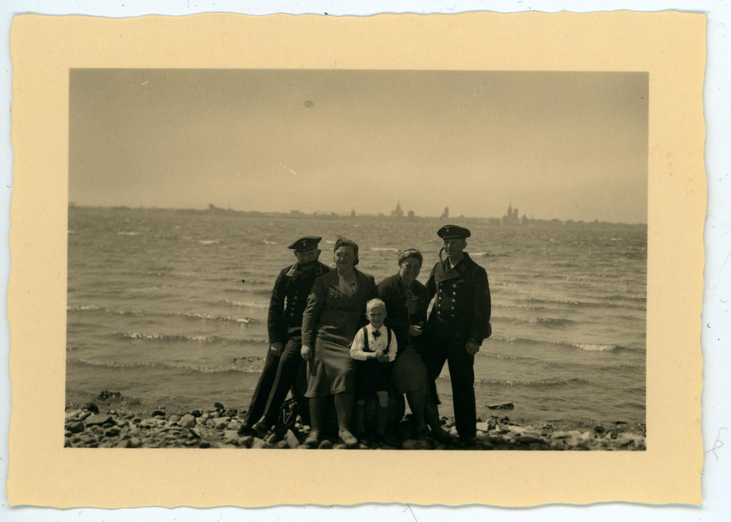 Kaks sõdurit, kaks naist ja poisslaps mererannal, taamal Tallinna siluett
