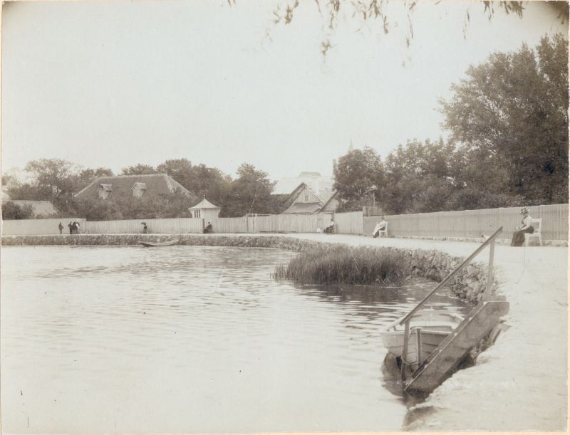 Foto. Vaikne kallas Haapsalus. Vaade promenaadile Väikese viigi lõunakaldalt. Pinkidel istumas suvitajad.
u 1900.