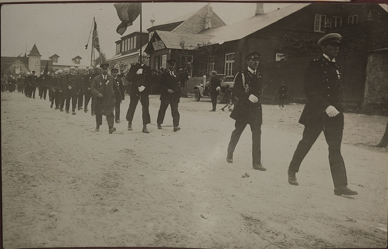 Tuletõrjemundrites meeste kolonn lippudega marssimas