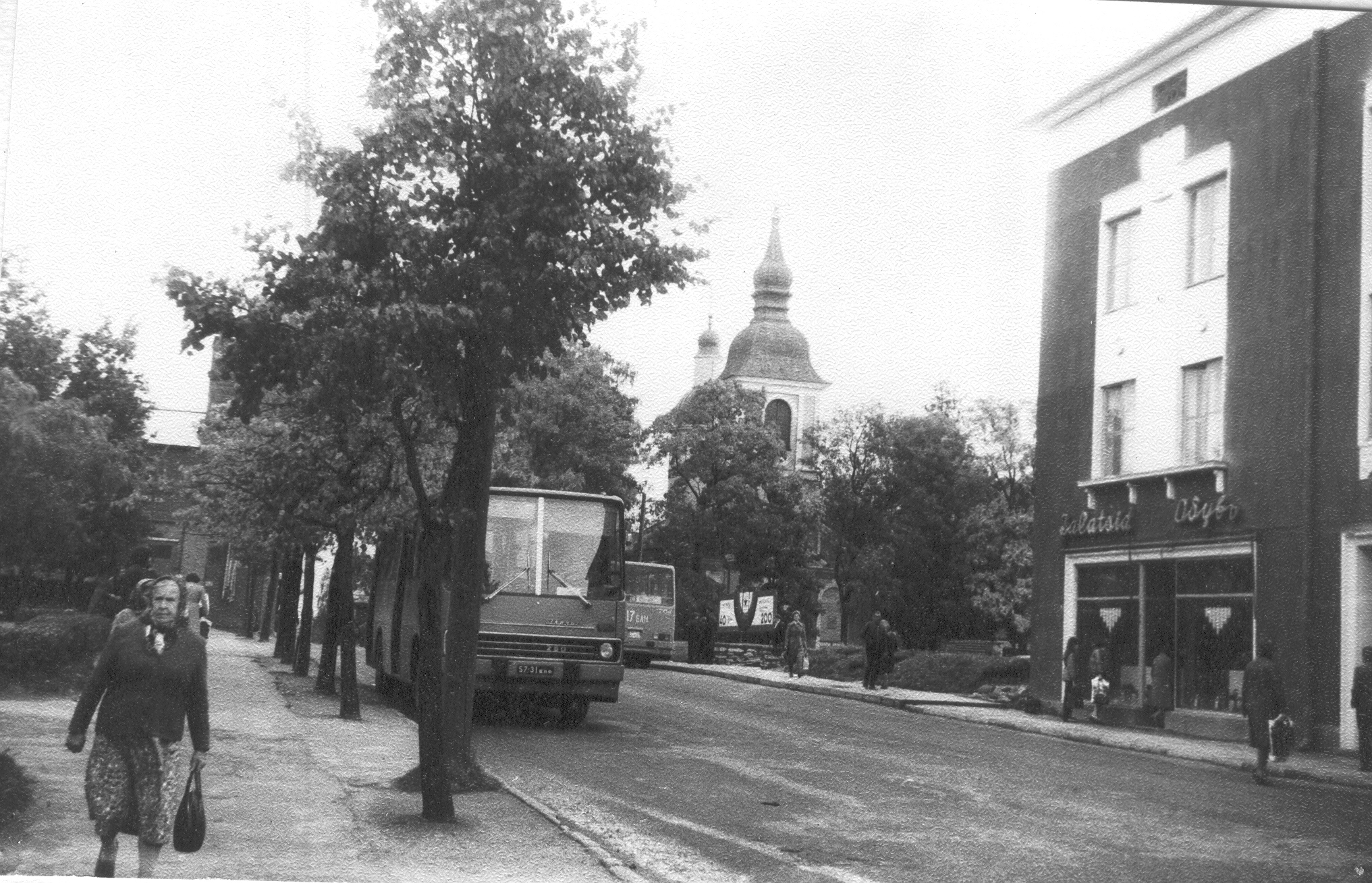 Foto Linnaliinide autobussipeatus, EAÕK  Võru Jekaterina kirik,Riigipanga Võru osakonna maja kauplustega Tartu t. 25  ,1983.a. sügisel.