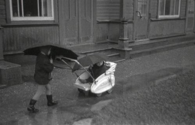 A small boy with a little brother in the parent's car, with rain weather on the street, both rainbow 1967