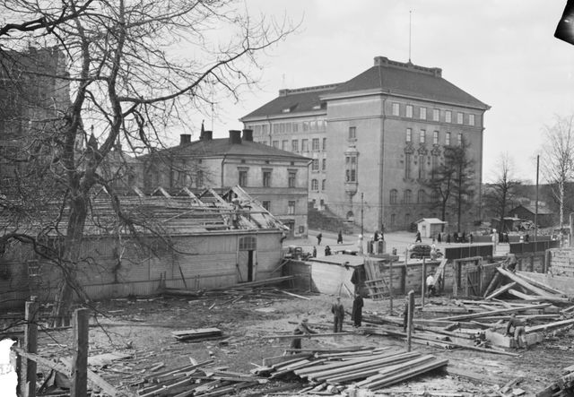 Kaisaniemen nykyinen ala-aste kuvattuna Unioninkadulta, taloja puretaan etualalla, vasemmalla nykyään Varsapuistikko ja etualalla Kaisaniemenkadun liikenneympyrä