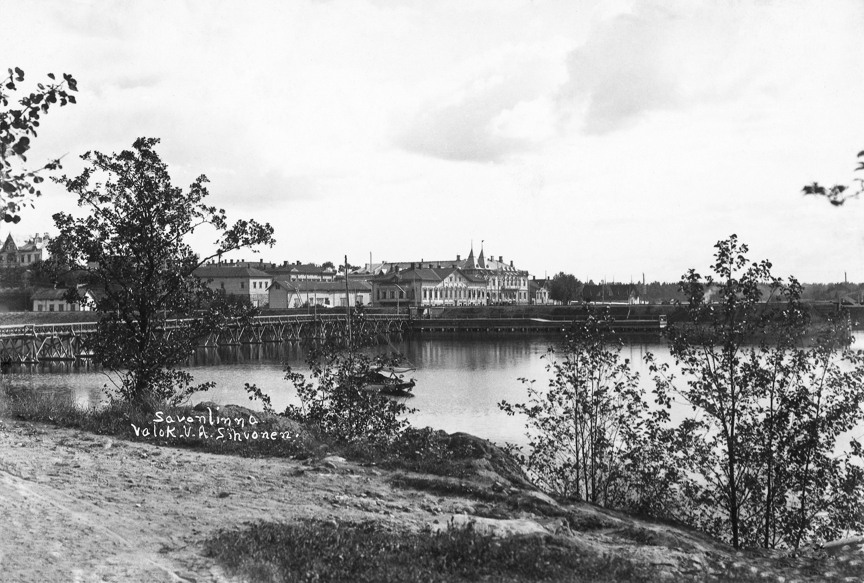Näkymä Kasinonsaarelta Koululahden yli kaakkoon. Vasemmalla Kasinonsaaren silta. Koululahden etelärannalla Sikion talo ja taustalla Seurahuone. kesä 1908. View from Kasinonsaari over Koululahti to the southeast