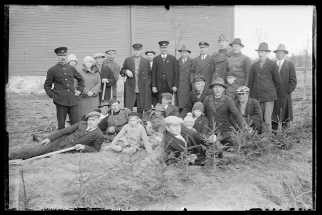 Puude istutamine ? - mehi, naisi ja lapsi labidatega noorte istikutega poseerimas