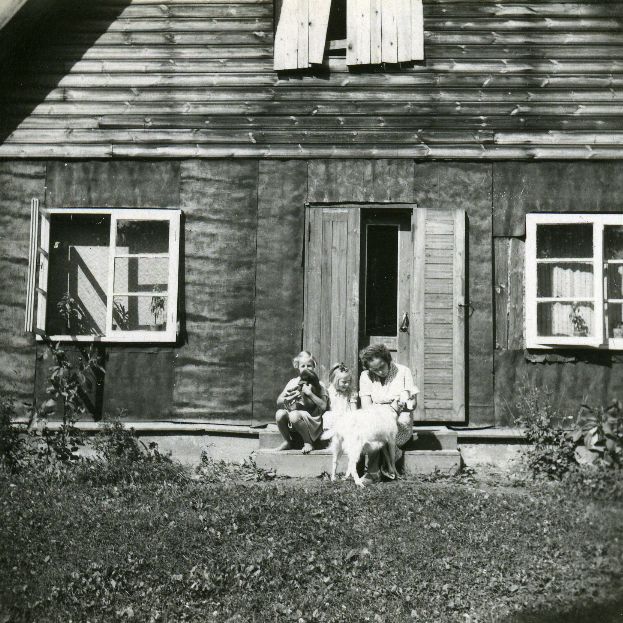 Betti Alver is sitting on the stairs of the house with children, goats and dogs grow. 1952