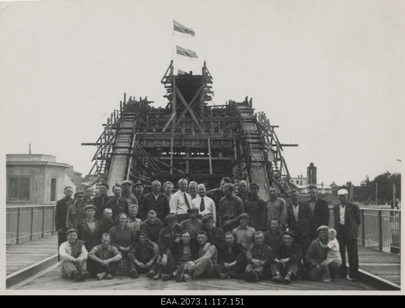 Construction of Pärnu Suursilla, builders in the case of drawing cards in the background of a bridge with flags, group photo