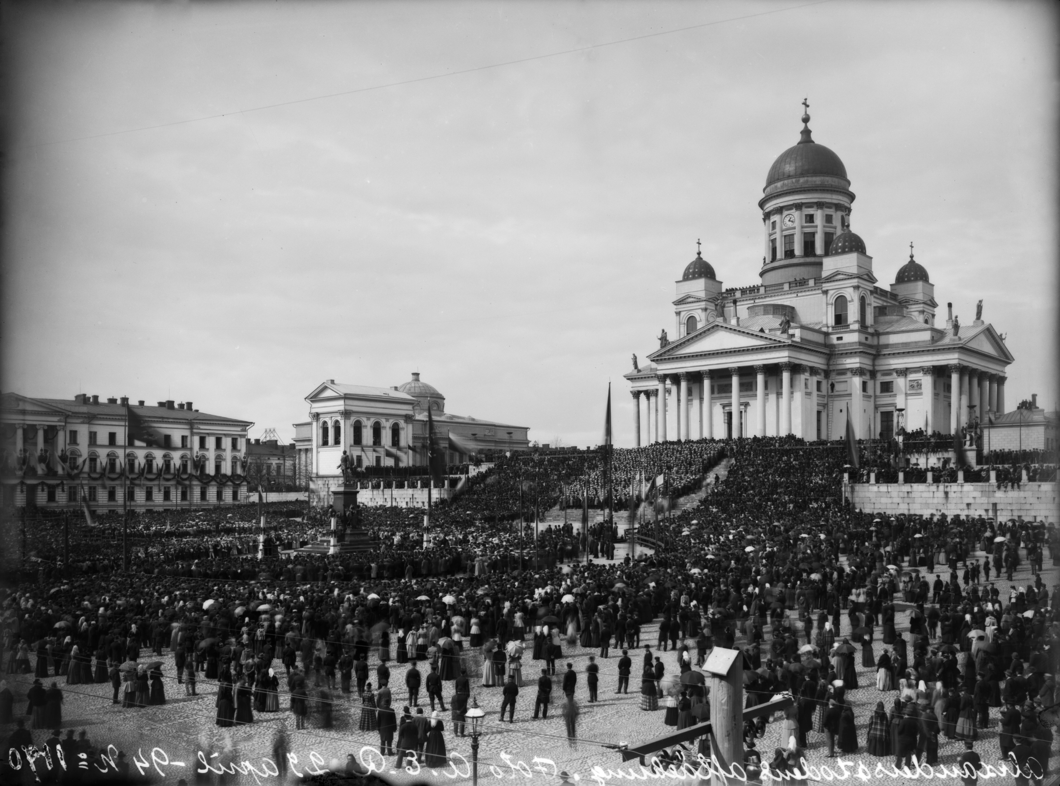 Aleksanteri II:n muistopatsaan paljastustilaisuus Senaatintorilla, taustalla Nikolainkirkko (=Suurkirkko, Helsingin tuomiokirkko) ja vasemmalla Keisarillisen Aleksanterin-Yliopiston (=Helsingin yliopisto) päärakennus.