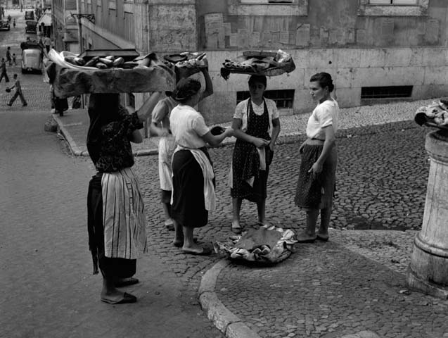 Women carry food on their heads on the street of Lisbon.