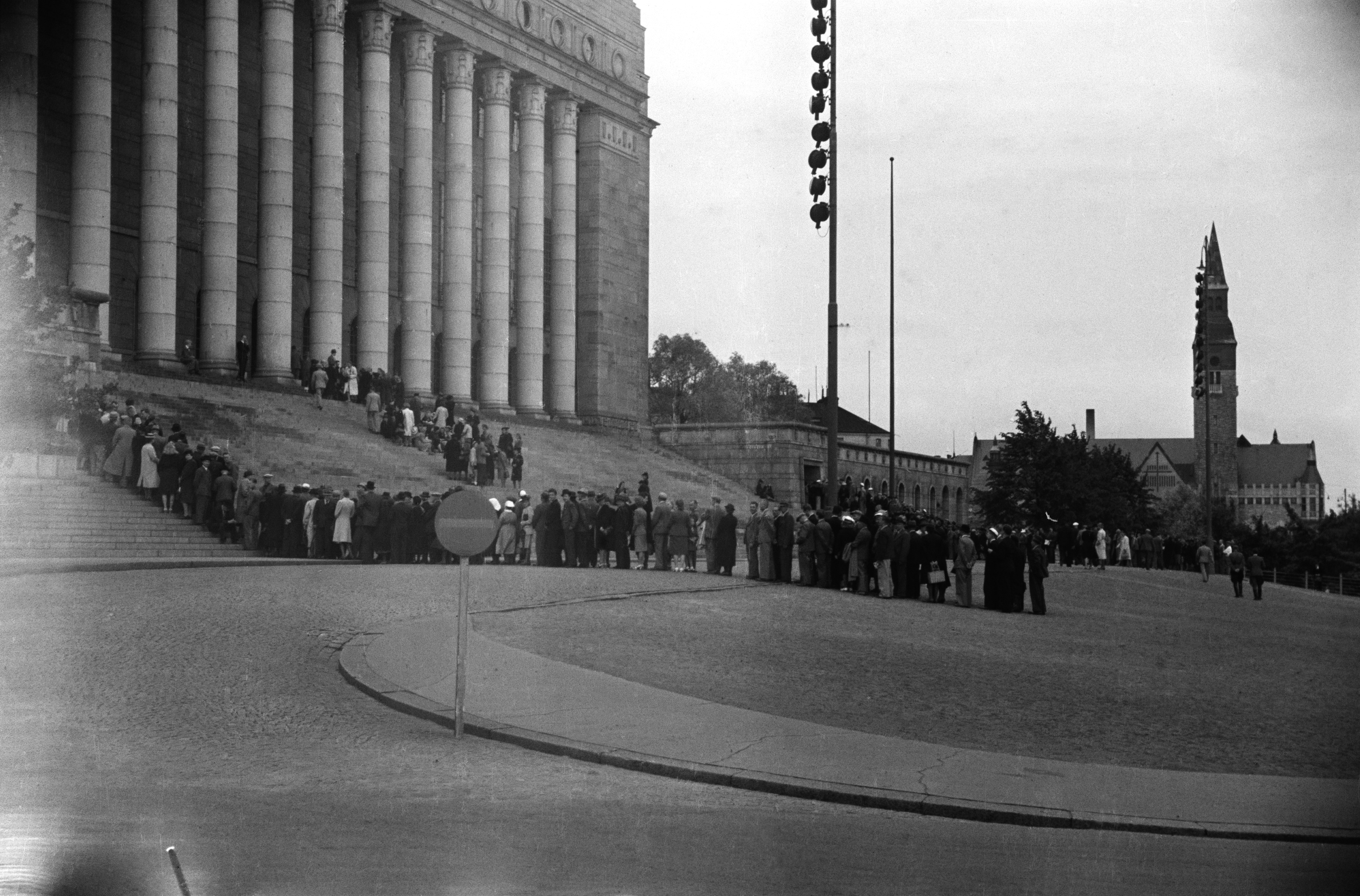 Välikysymys sotasyyllisyydestä Eduskunnassa.  Ihmiset jonottavat pääsyä yleisölehtereille.