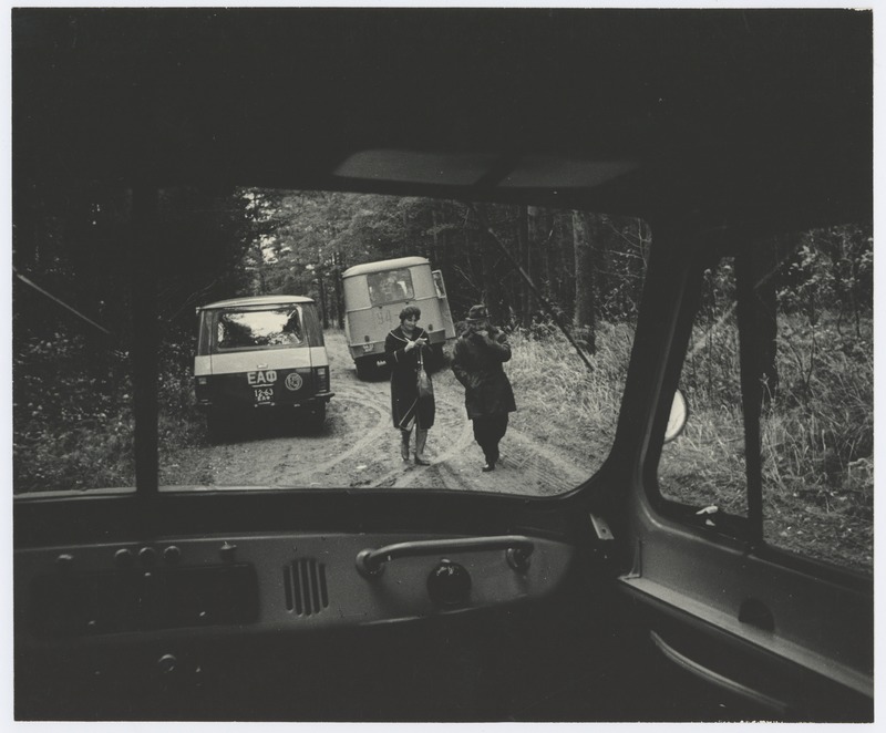 View through the car window: man and woman on the forest road.