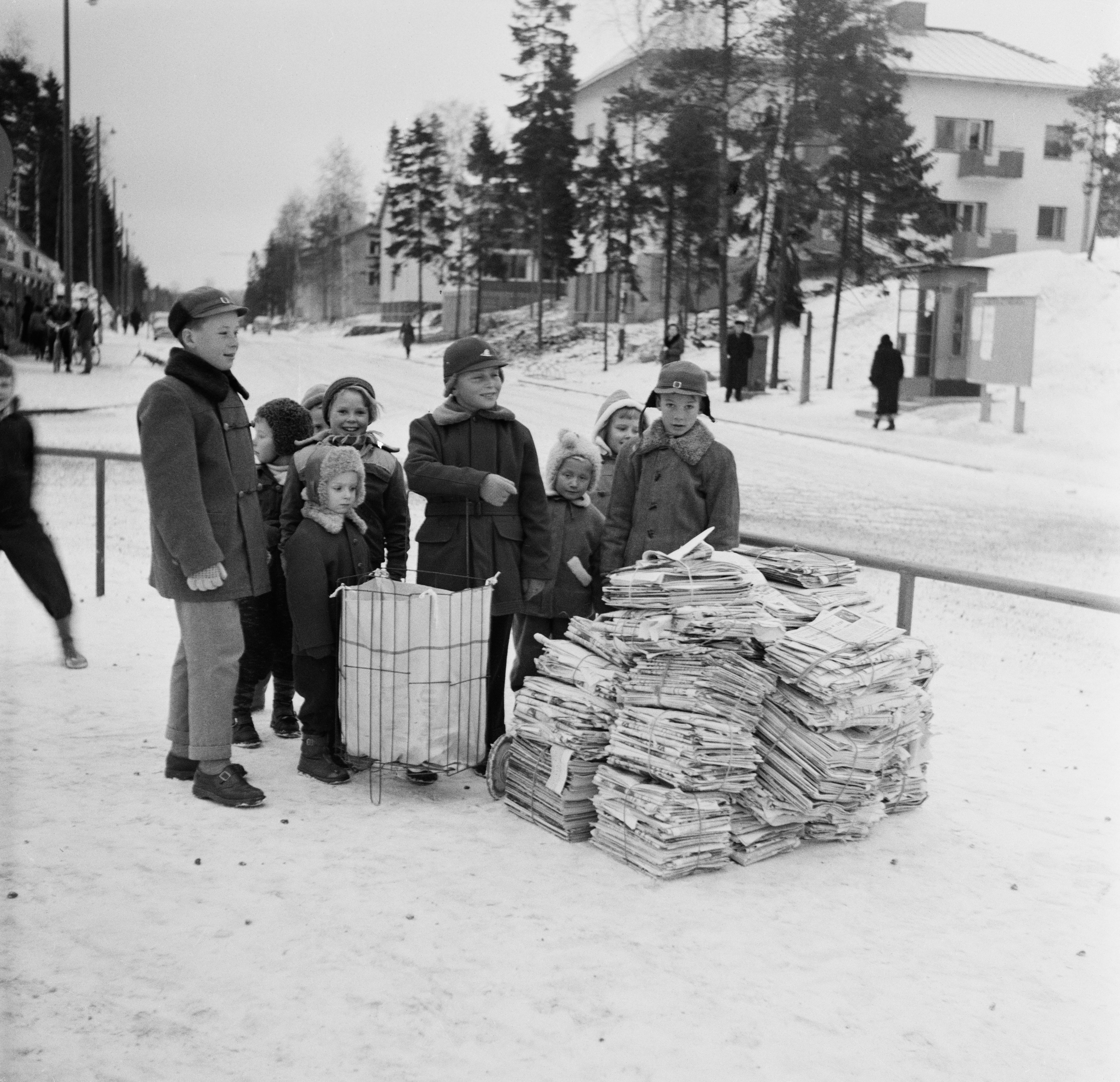 Koululaiset paperinkeräyspinojen kanssa Herttoniemessä Eränkävijäntorilla talvella 1957.
