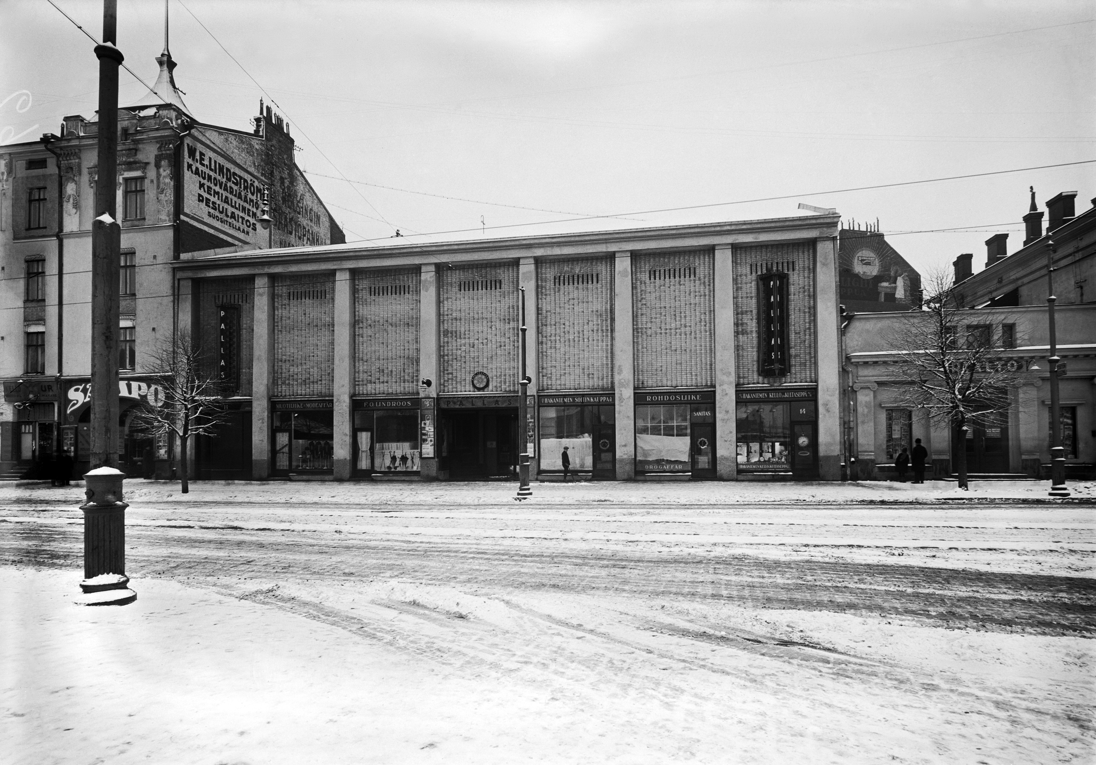 Siltasaarenkatu 14. Elokuvateatteri Pallas, muotiliike, F. O. Lindroosin liike, Hakaniemen soitinkauppa, Rohdoskauppa sekä Hakaniemen kello- ja kultaseppä. Oikealla elokuvateatteri Rialto, vasemmalla elokuvateatteri Sampo. Talo rakennettu n. 1925 - 26, purettu 1958.