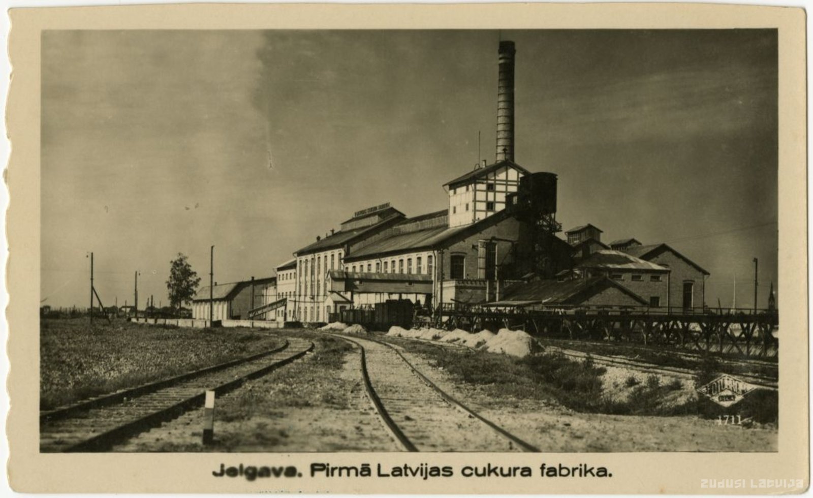 At the bottom of the open, in the middle of the script: "Jelgava. First Latvian sugar factory."
