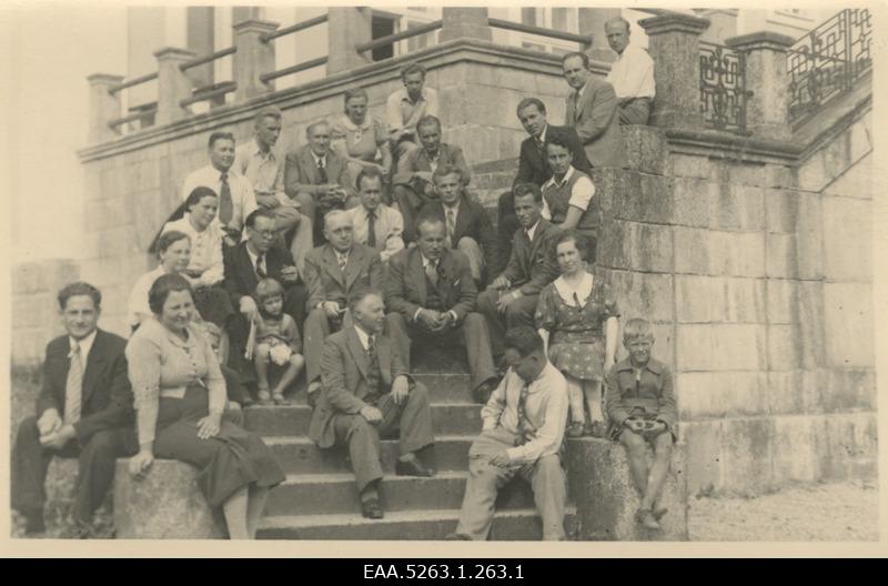 Participants from the summer days of the characters are sitting on the stairs of Ravila Manor