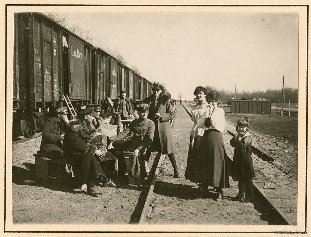 [German officers conversing with women and child in rail yard]