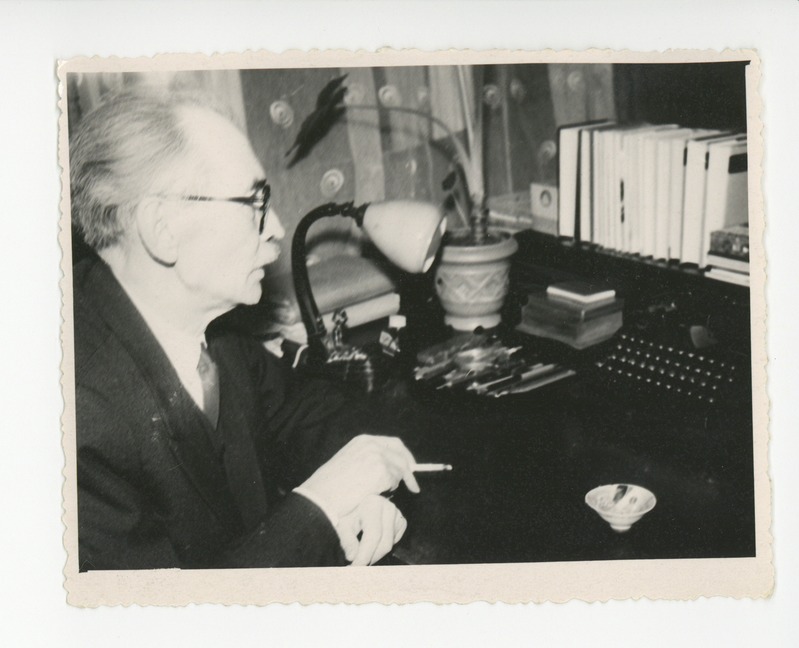 Friedebert Tuglas oma töökabinetis kirjutuslaua taga töötamas ja suitsetamas