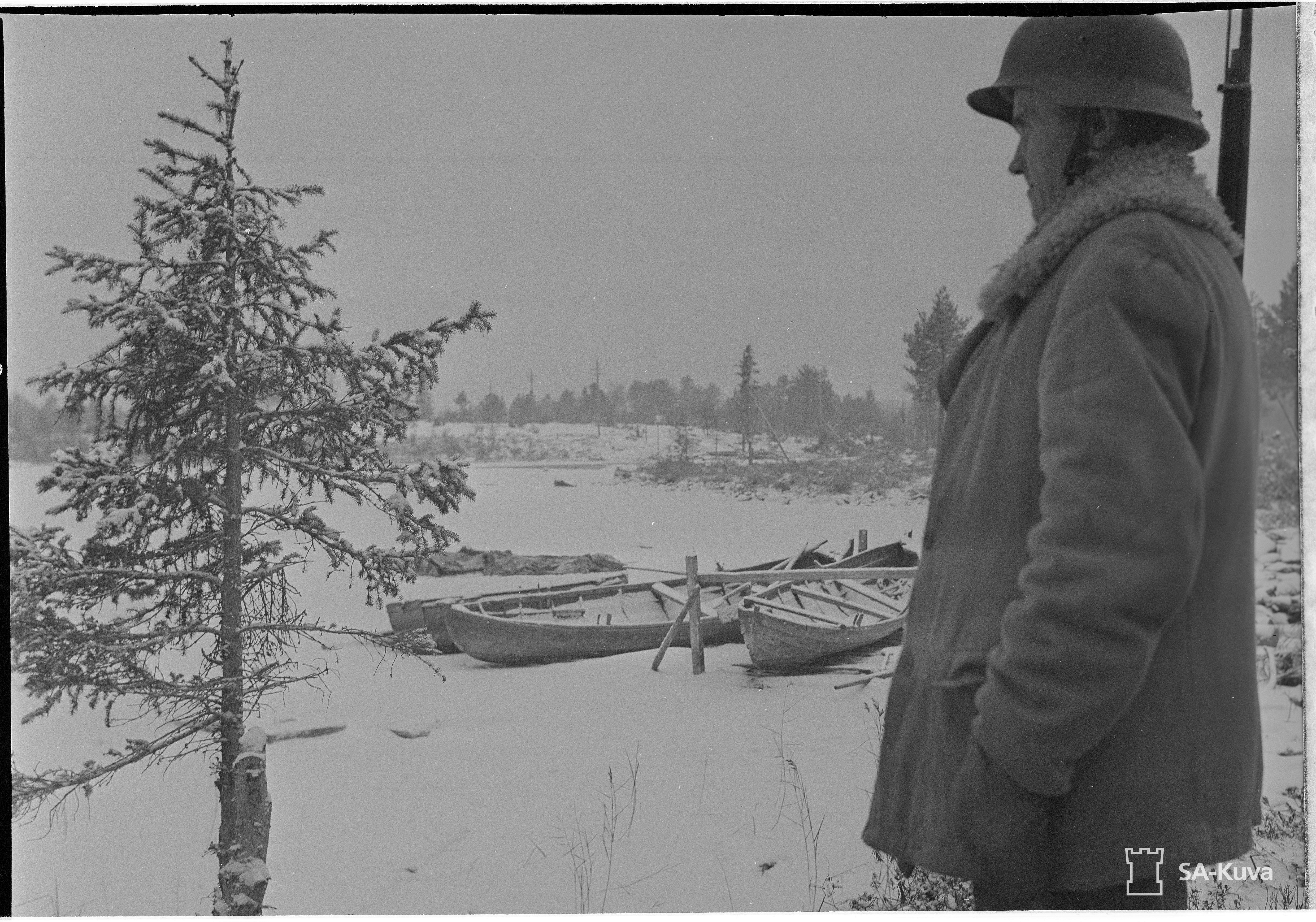 A Finnish soldier in guard on the beach of Tulppajärvi, the first snow has arrived and boats have been drawn from the frozen lakes to the countries.