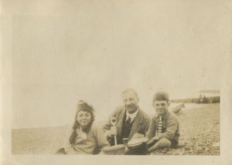 Man and two children on the beach with buckets and spade