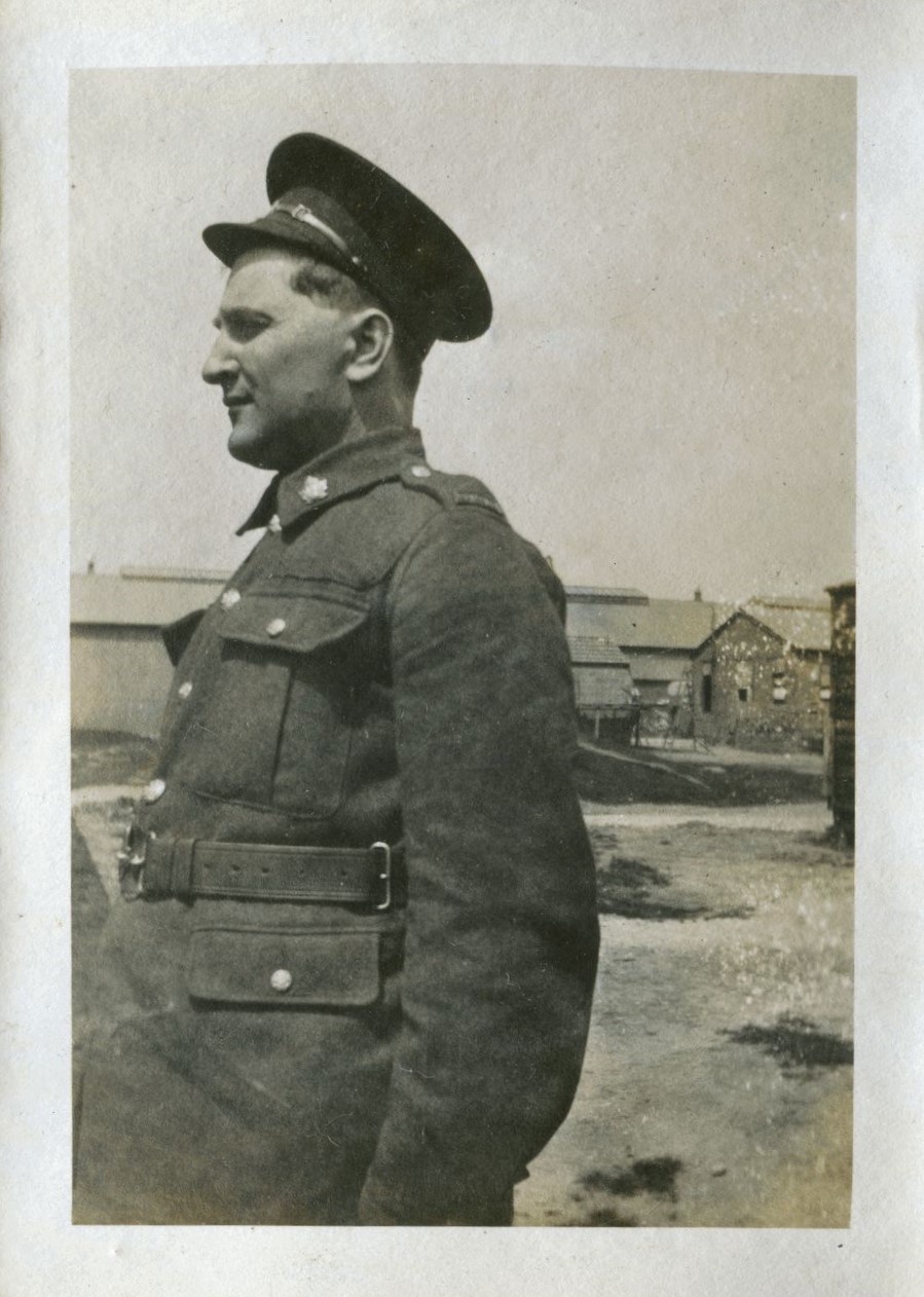 Profile of man in uniform with huts in the background, 'Tin Town' Brockenhurst, 1918