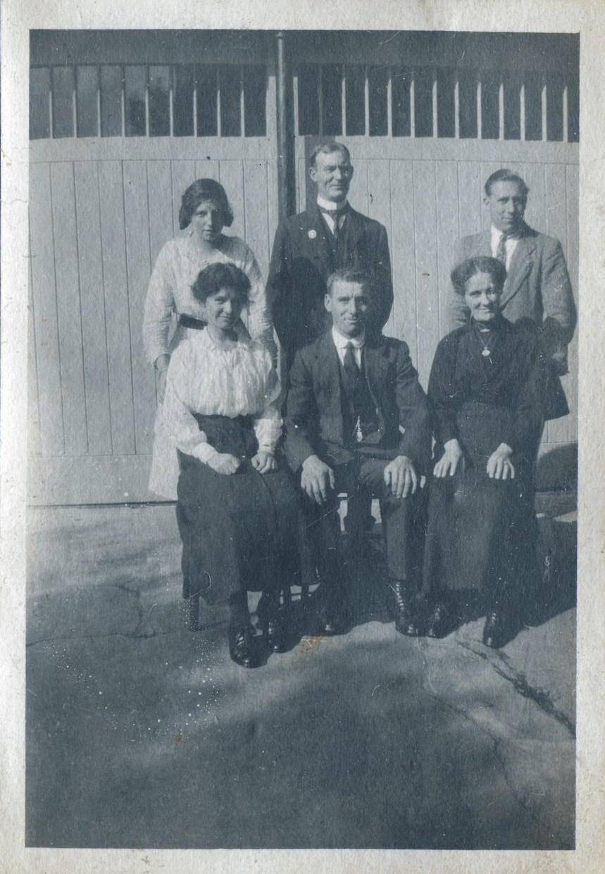 Posed group of a woman and two men standing and two women seated either side of a man in front, St Mary's Stables, Bedfont, Middlesex, 1920