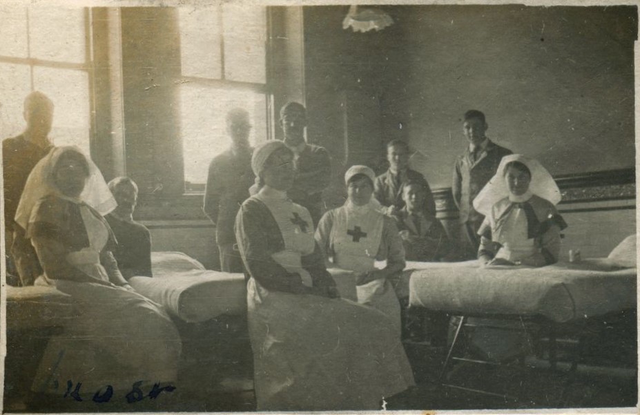 Seated nurses and patients standing around beds