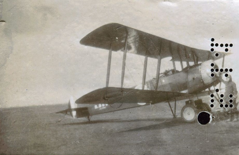 Avro 504 bi-plane with man standing by the propeller